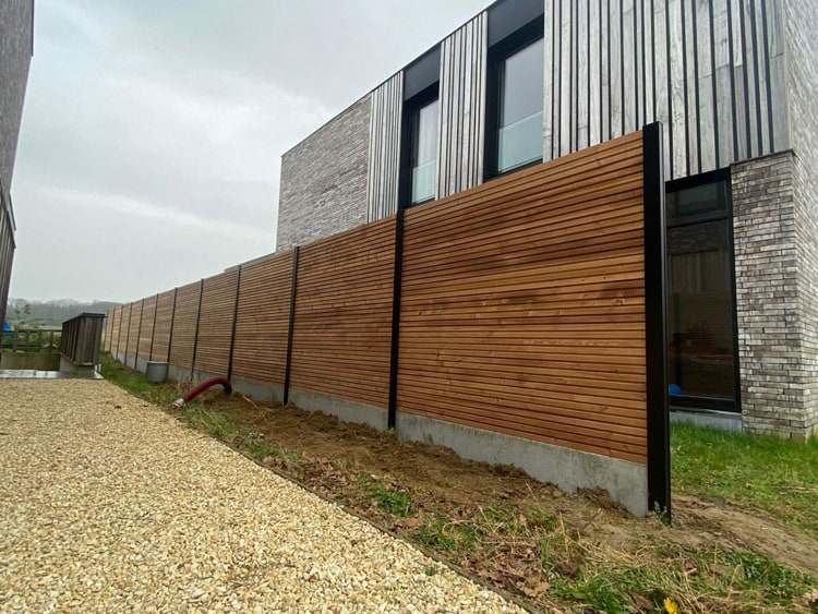 Thermowood hekwerk met fijne horizontale latten in een warme bruine tint langs een moderne woning